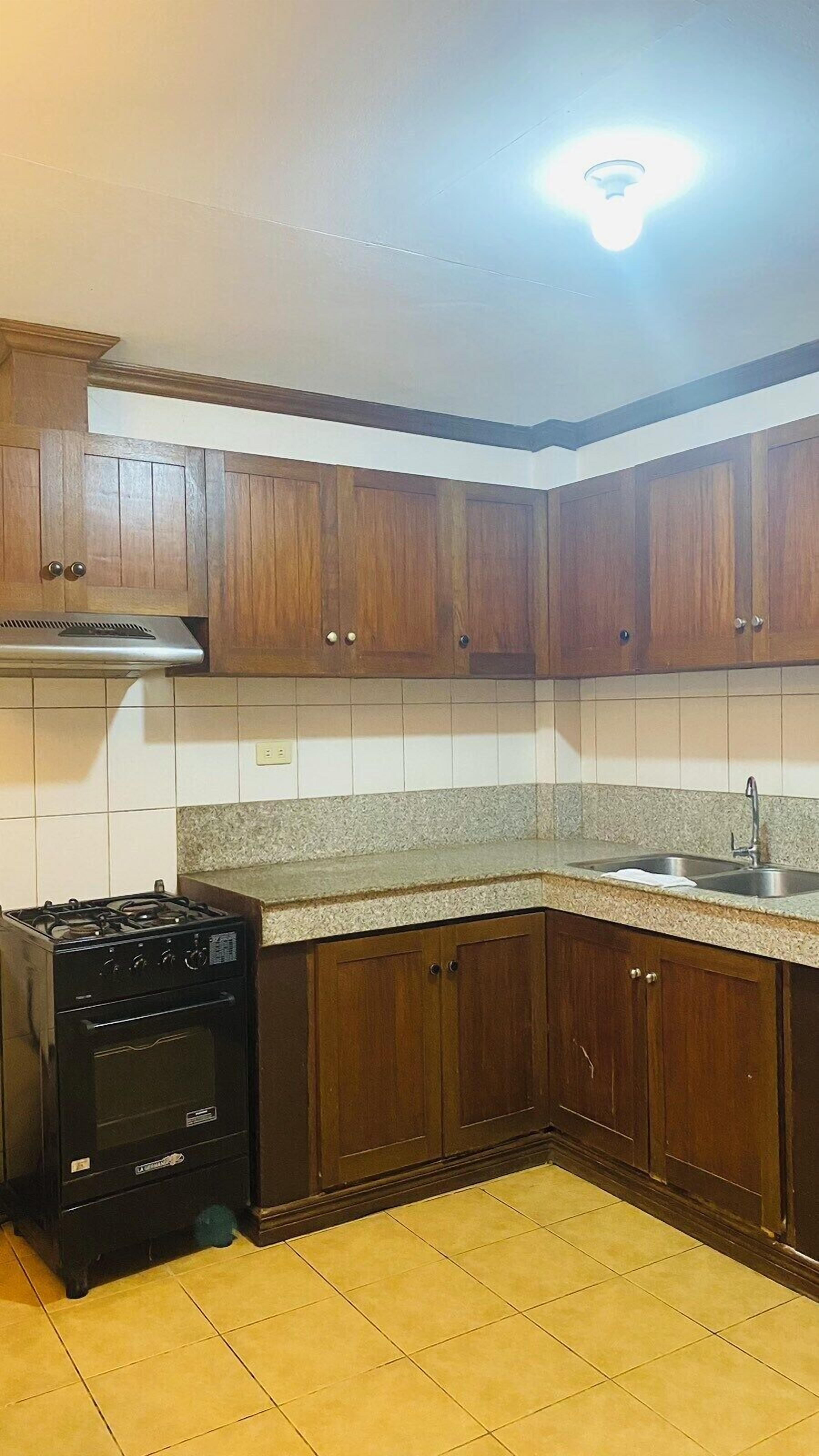 A kitchen with wooden cabinets, a stove, and a tiled backsplash.