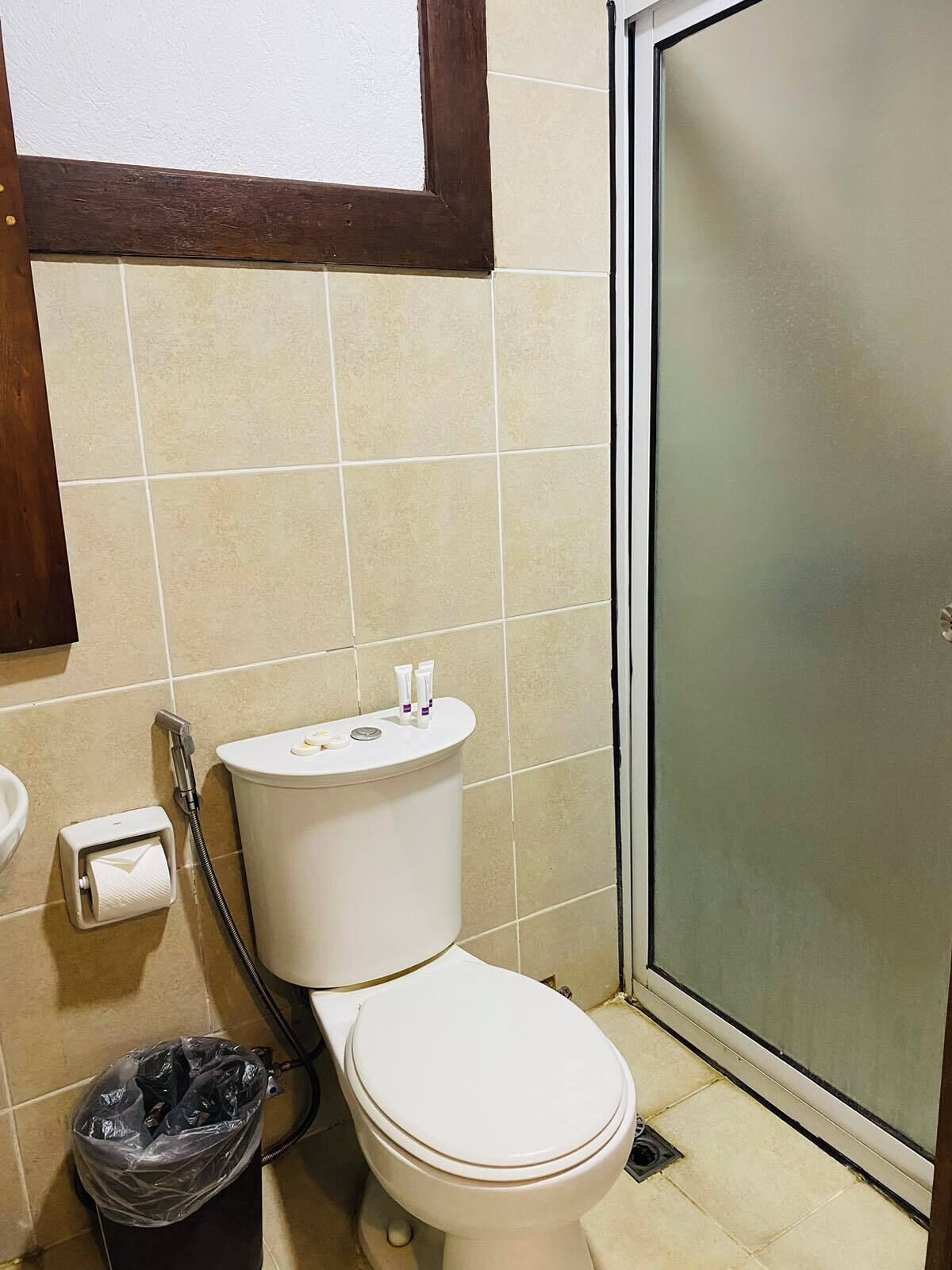 Un baño con inodoro, ducha y cubo de basura.