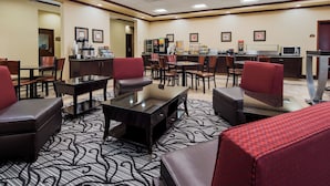 Un hall d’hôtel avec des coins salon, un espace où l’on peut se servir du café et un four à micro-ondes.