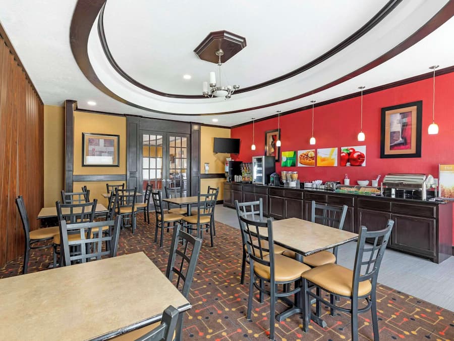 A restaurant with tables and chairs, a counter with a menu, and a television on the wall.