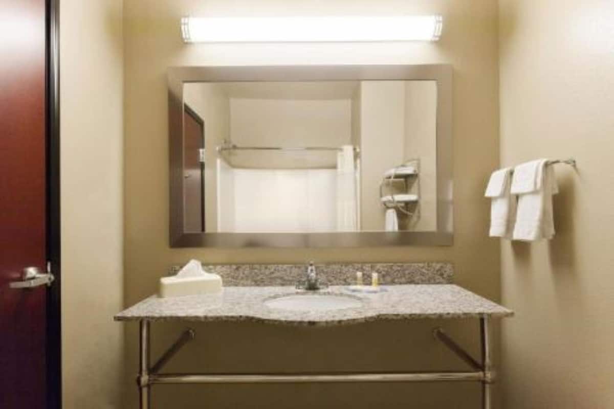 A bathroom with a sink, mirror, towel rack, and a door.