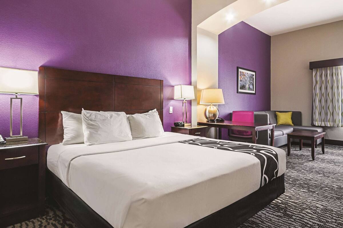 Une chambre d’hôtel avec un grand lit, un bureau, une chaise et un canapé.