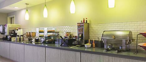 A self-service breakfast bar with coffee machines, a salad bar, and a grill.