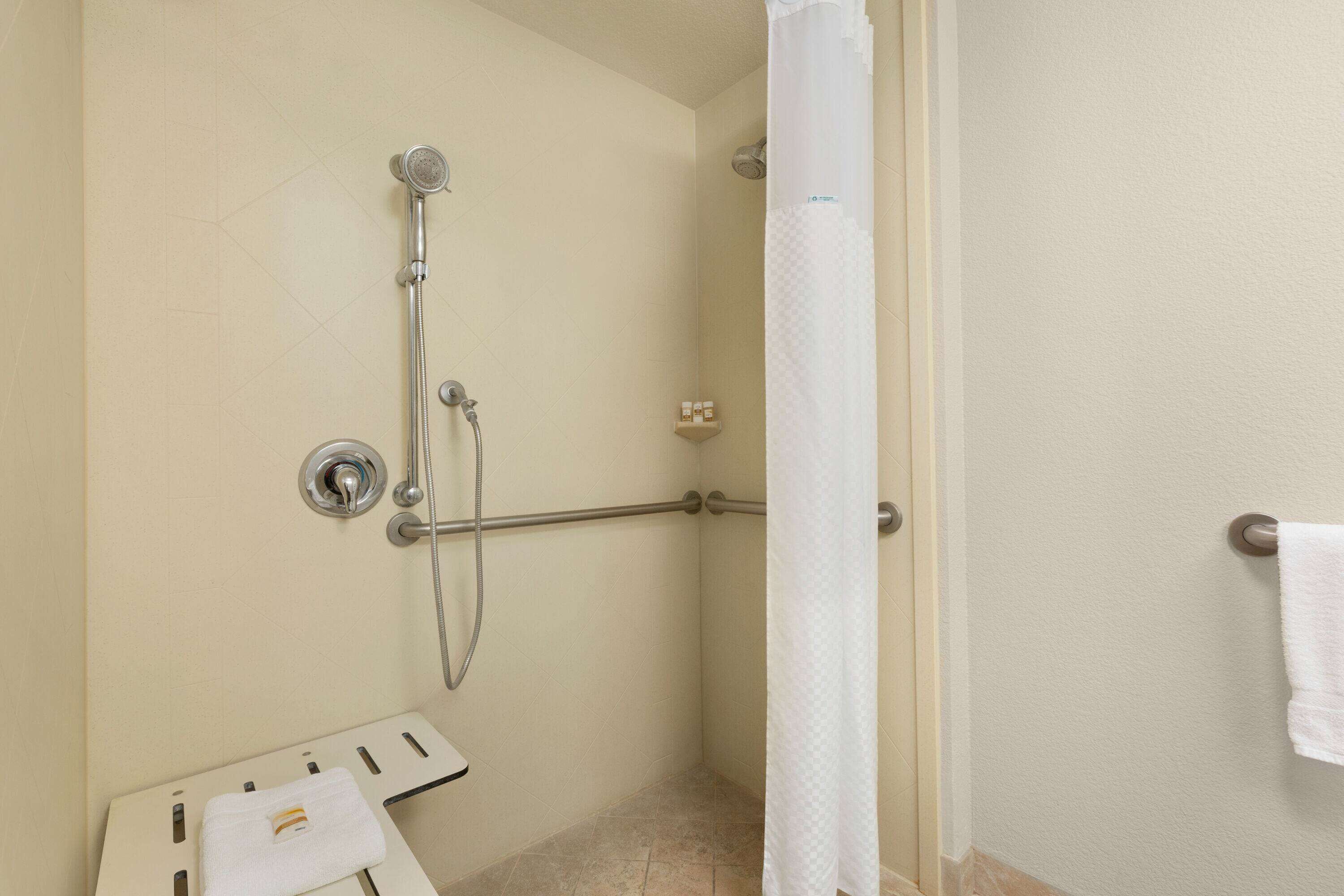 A shower area with a handheld showerhead, a wall-mounted faucet, and a towel rack with a towel.