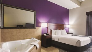 Een hotelkamer met een groot bed, een aparte badkamer met een badkuip en een grote spiegel.