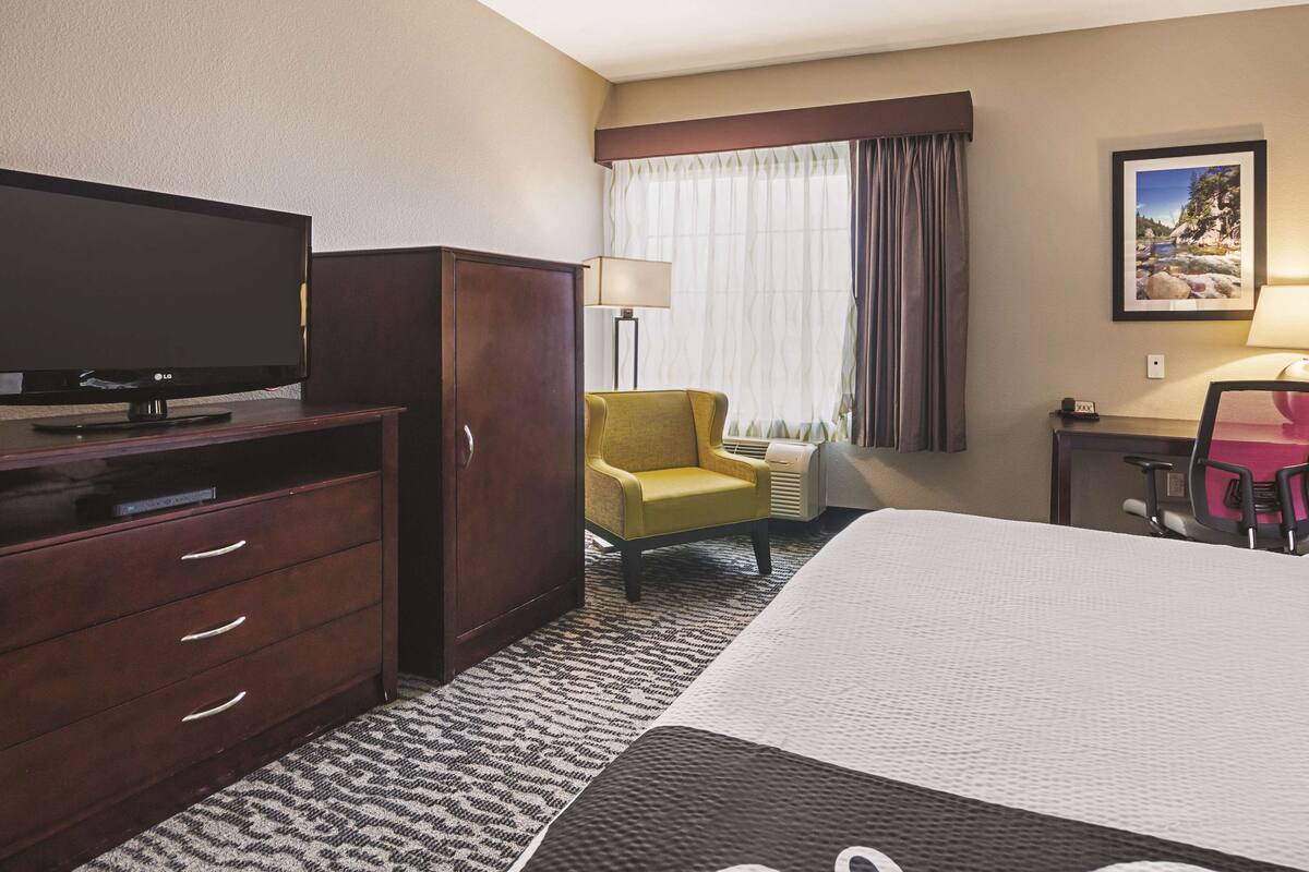 Une chambre d’hôtel équipée d’un lit, d’une télévision, d’un bureau, d’une chaise et d’une lampe.
