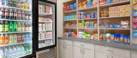 Expositor refrigerado para bebidas com diversas opções e prateleira de lanches com salgadinhos e outros petiscos.