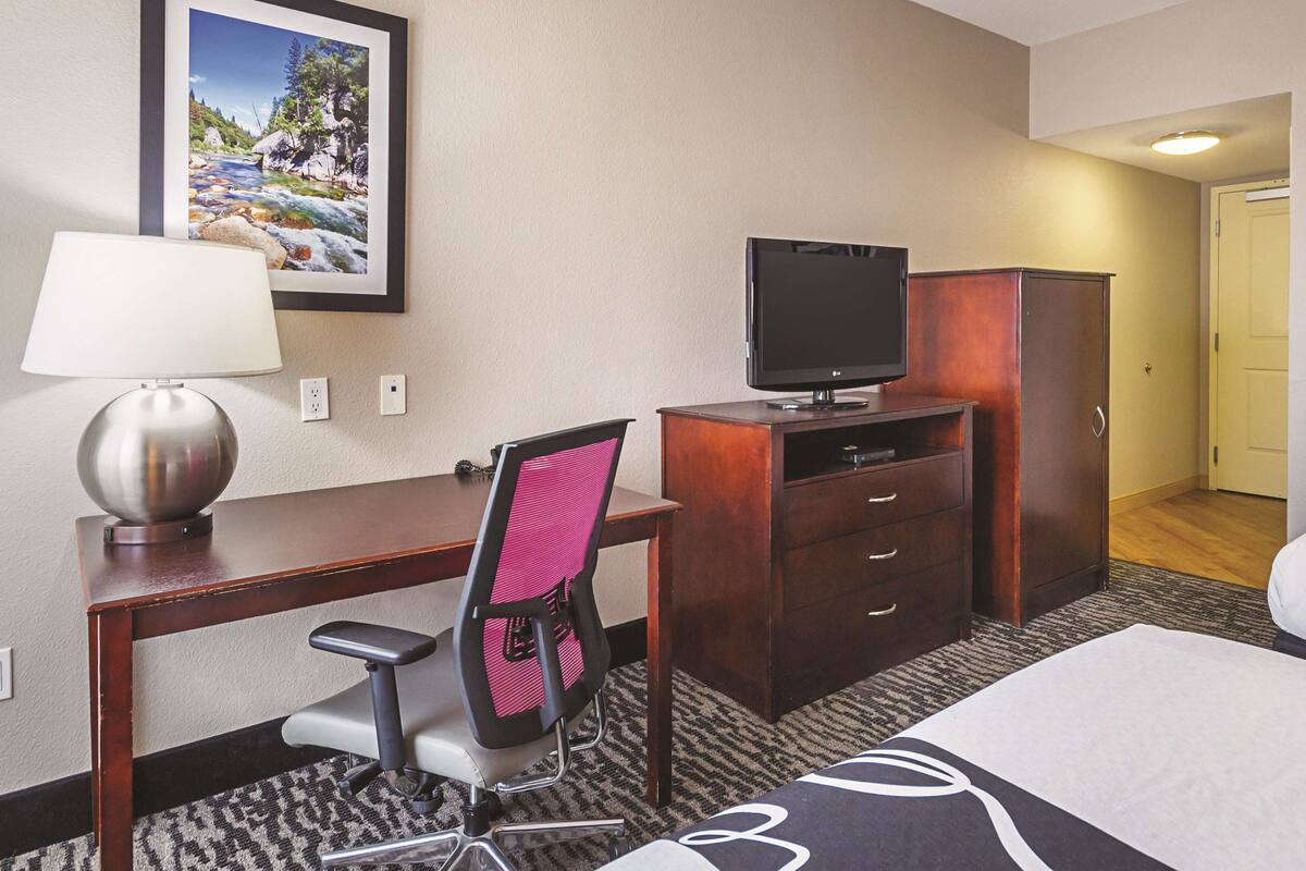 Une chambre d’hôtel équipée d’un bureau, d’une chaise, d’une télévision, d’une armoire et d’un lit.