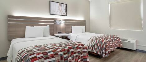 Habitación de hotel con dos camas, una mesita de noche, una lámpara de pared y una ventana con persianas.