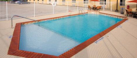 A rectangular pool with a white fence, a lifebuoy, and a 'NO DIVING' sign.