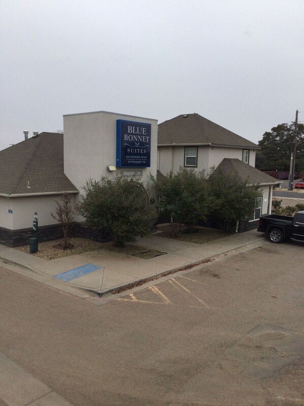 A building with a sign for Blue Bonnet Suites, indicating it offers extended stay and kitchenette facilities. - Blue Bonnet Suites Extended Stay Lubbock, Texas (Lubbock)