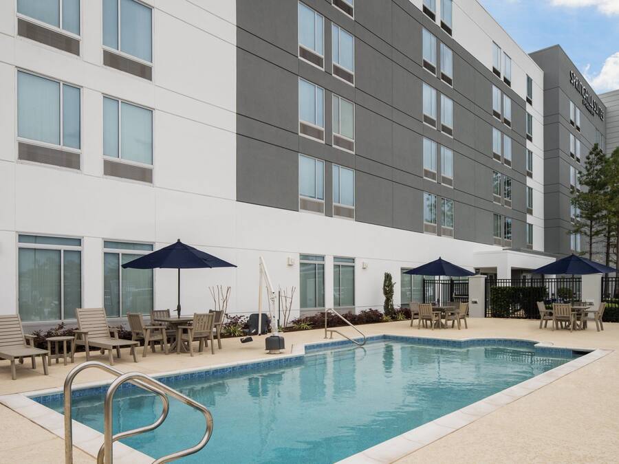 A hotel with a swimming pool, outdoor seating, and a modern building facade.