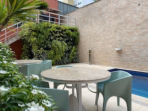Eine Terrasse mit Pool, Sitzgelegenheiten im Freien und einer Backsteinmauer.