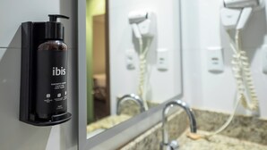 A bathroom with a black bottle of ibis liquid soap, a mirror, and a hairdryer. - ibis Styles Belém Nazaré (Belém)