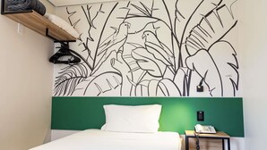 Een kamer met een bed, een groen hoofdeinde, een muurschildering van vogels en begroeiing, een nachtkastje met een lamp en een telefoon.