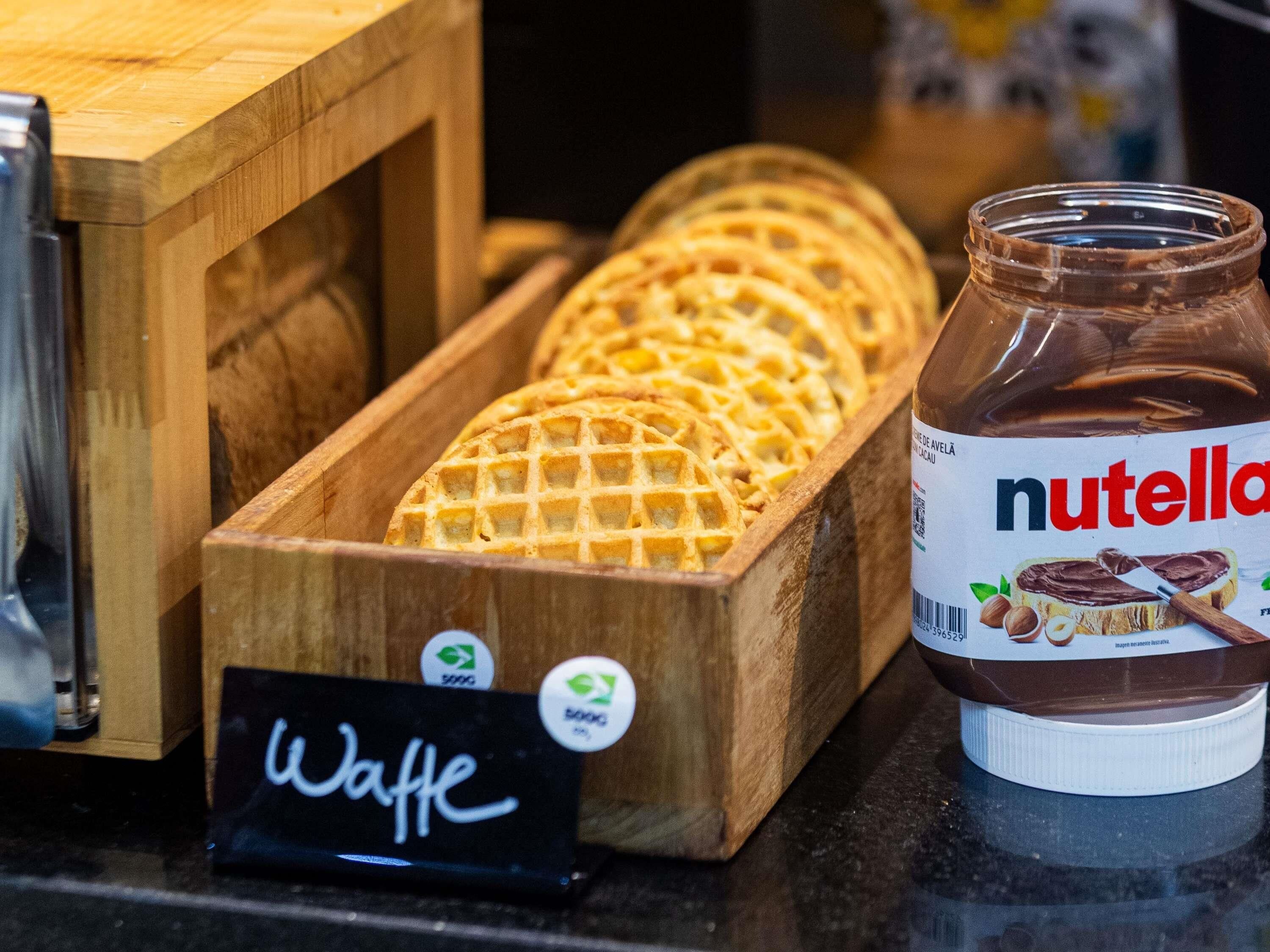 A wooden box labeled "Waffle" containing waffles, a jar of Nutella, and a sign with the word "Waffle".