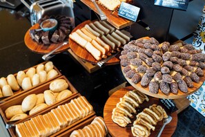 A variety of baked goods displayed on wooden trays, including bread, pastries, and cookies.