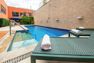 Piscina com espreguiçadeiras e porta-toalhas.