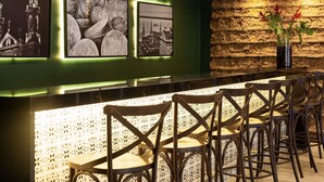 Een bar met een groene wand, ingelijste foto's en een achtergrond van natuursteen.