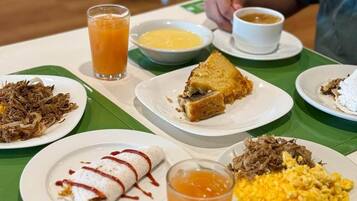 Una mesa con diversos platos, como un burrito, una rebanada de pan y una fuente de huevos revueltos.