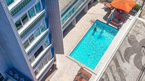 Ein modernes Gebäude mit Pool auf dem Dach, Außenbereich mit Sitzgelegenheiten und freiem Blick auf den Pool.