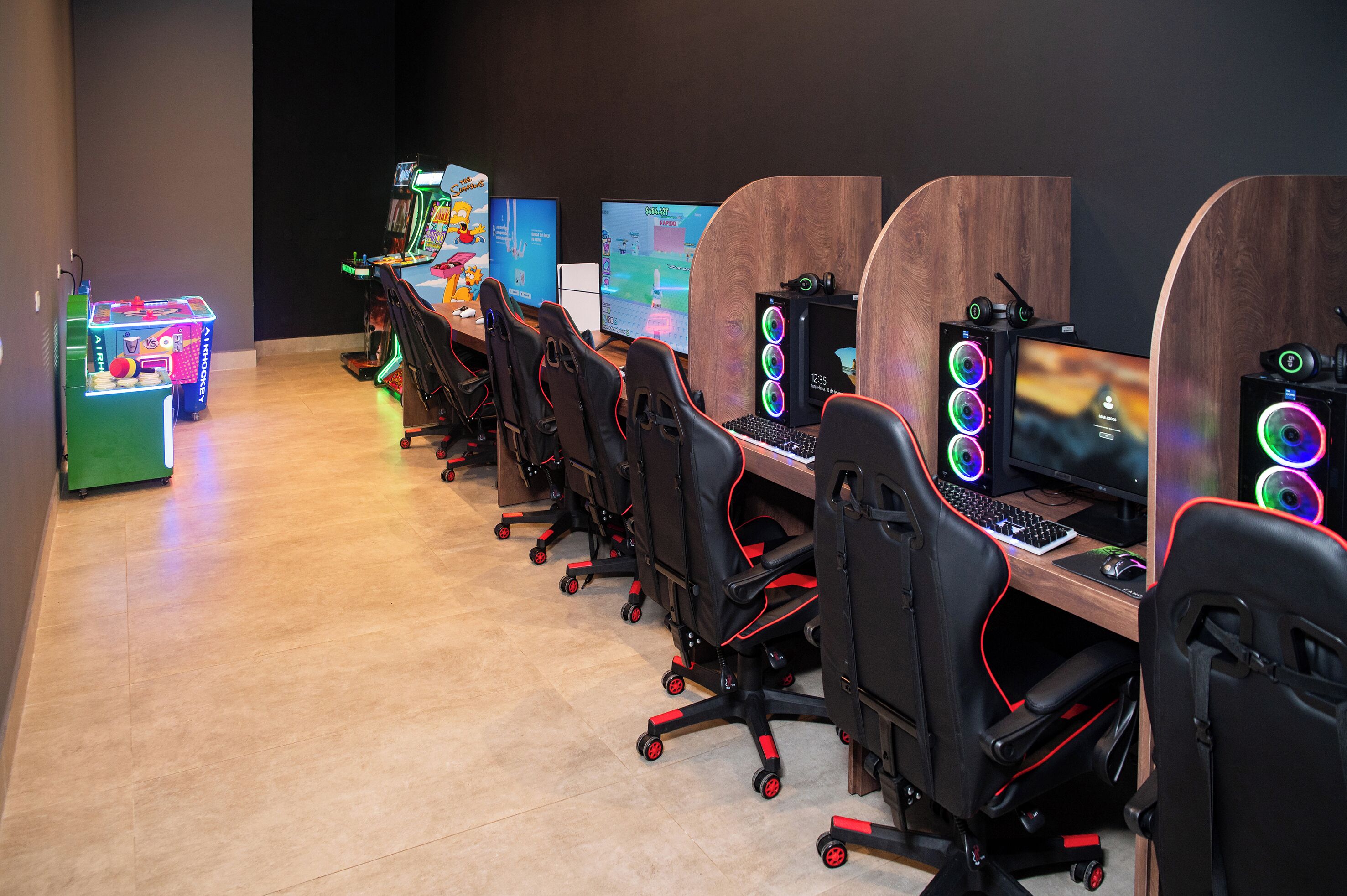 Eine Reihe von Gaming-Stationen mit Stühlen, Computern und Arcade-Automaten.