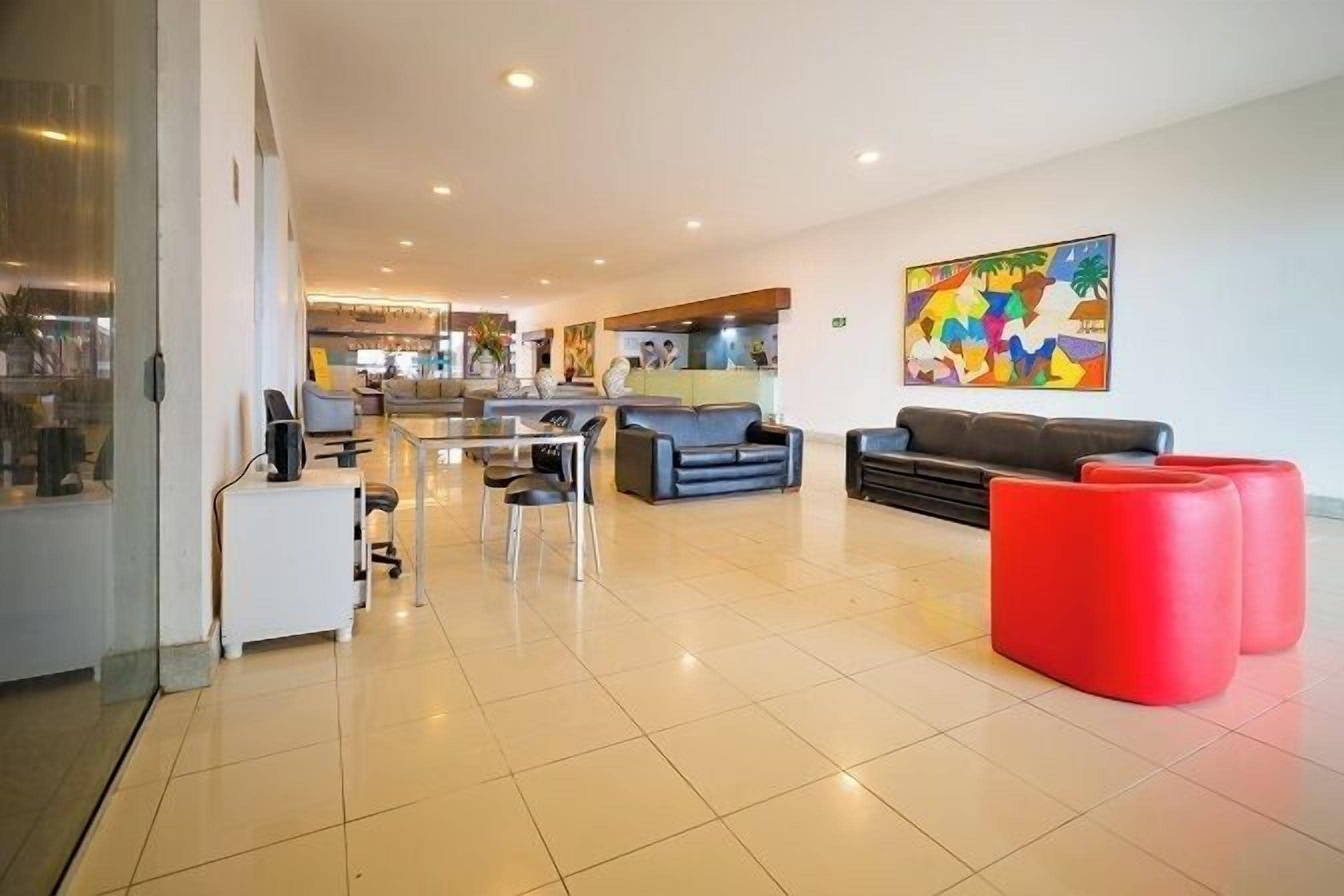 A modern lobby with a reception desk, seating area, and a colorful abstract painting.