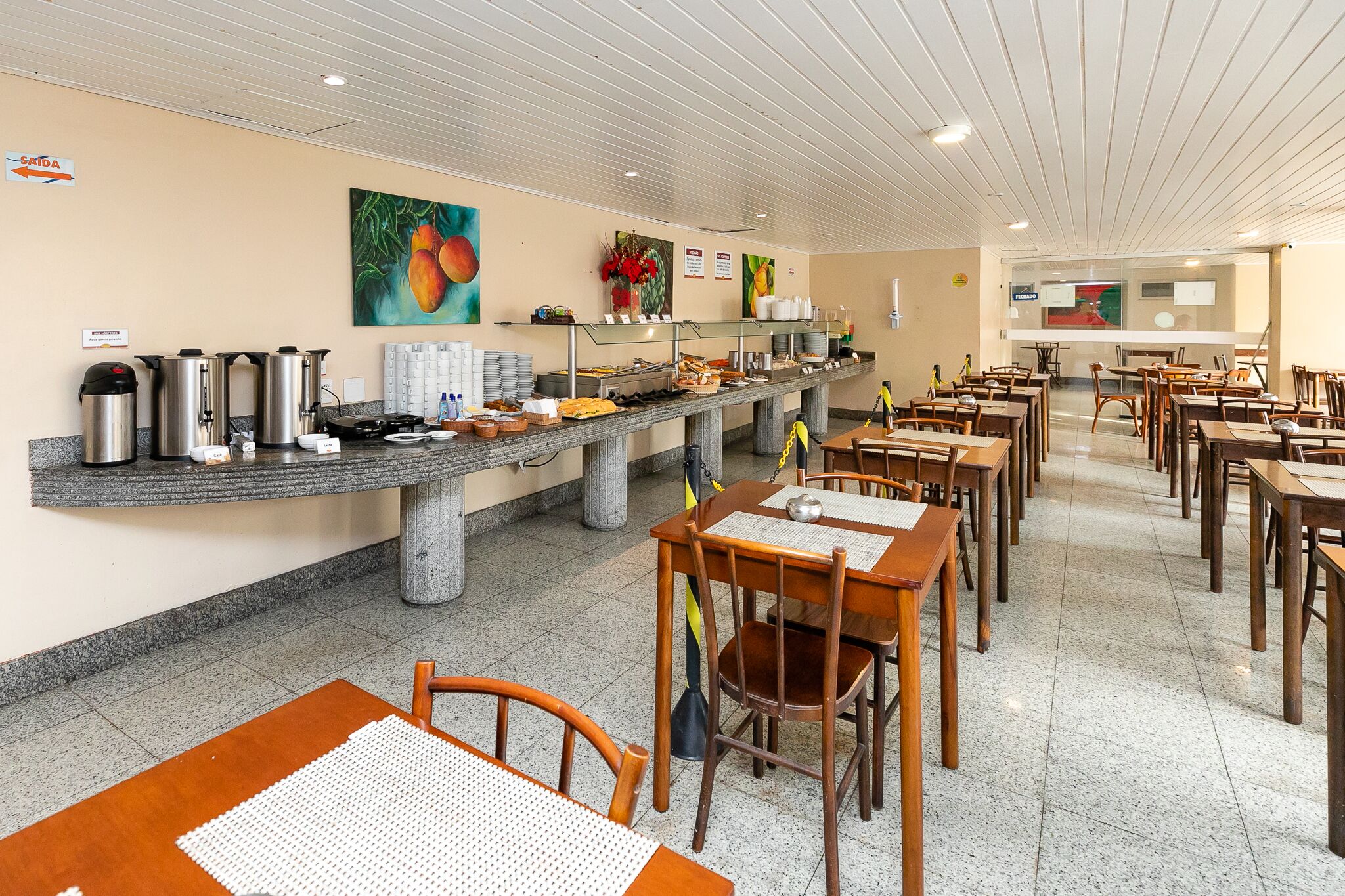 A cafeteria with a long counter, various food items, and seating arrangements.