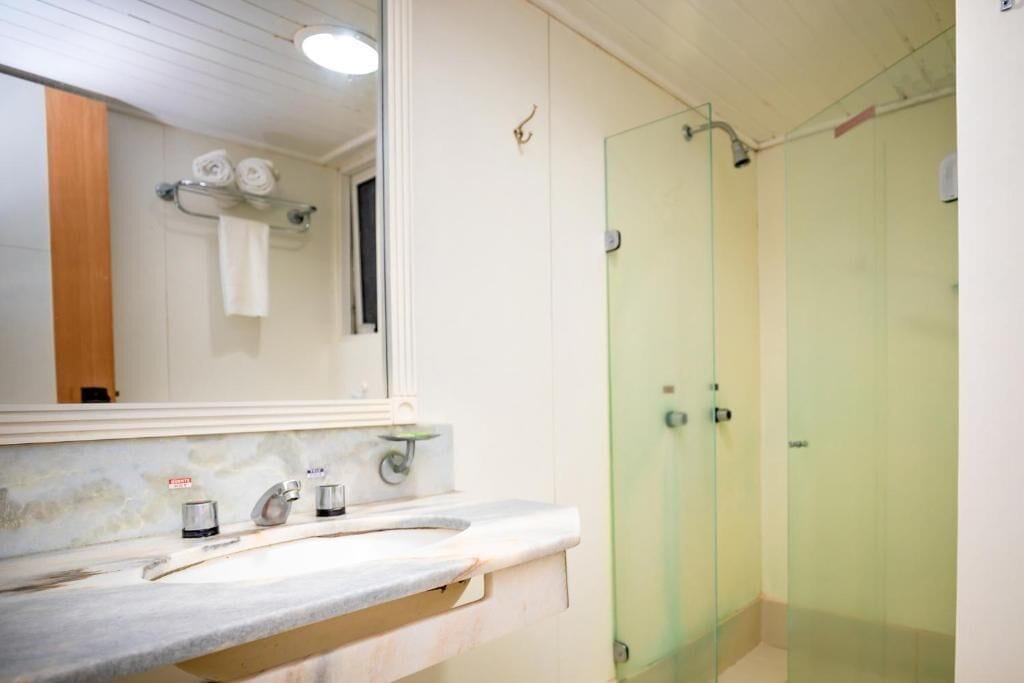 A bathroom with a white sink, a mirror, and a glass-enclosed shower stall.