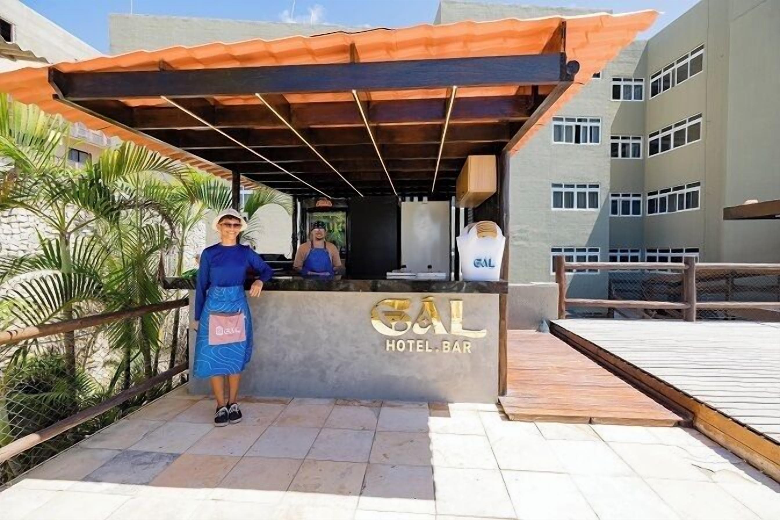 A hotel bar with a sign, a reception desk, and a covered outdoor area with a wooden deck.