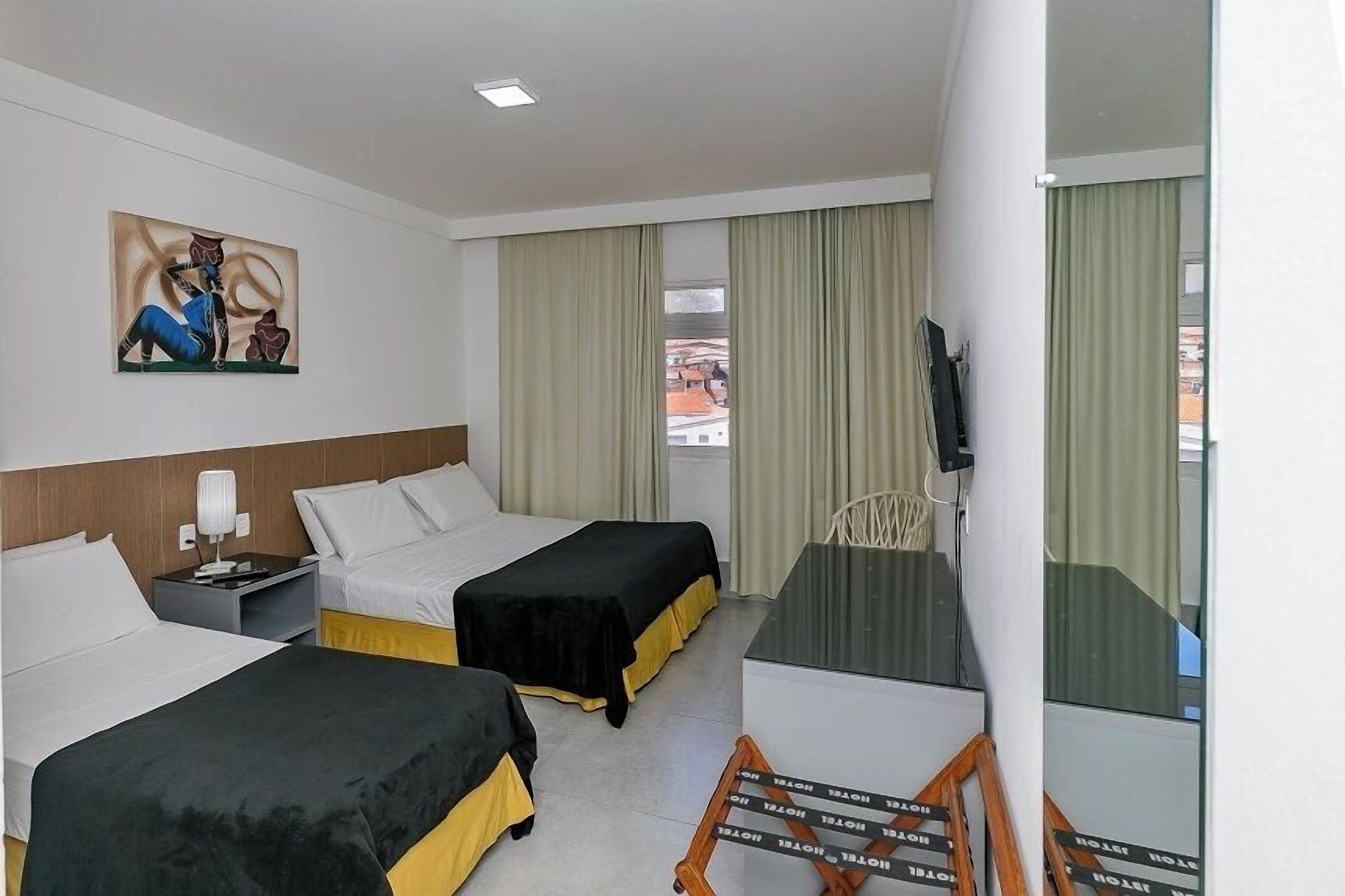 A hotel room with two beds, a desk, a chair, a television, and a painting on the wall.