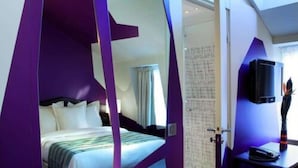 A modern hotel room with a bed, a television, and a shower area. - Cristal Champs Elysees (Paris)