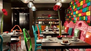 A restaurant with colorful chairs and tables, a vibrant wall, and a modern interior design. - Cristal Champs Elysees (Paris)