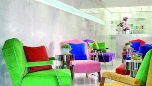A modern lobby with colorful chairs and a glass coffee table. - Cristal Champs Elysees (Paris)