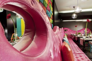 A vibrant restaurant interior with a pink, curved seating area and colorful decor. - Cristal Champs Elysees (Paris)
