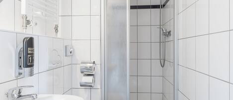 Een moderne badkamer met een witte wasbak, toilet en een douchecabine met glazen wanden.