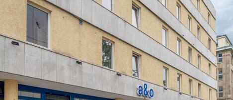 Un edificio de varios pisos con fachada amarilla y ventanas de marco azul.