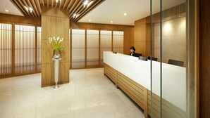 A reception area with a wooden reception desk, a vase with flowers, and a sliding door in the background. - The K-Hotel Seoul (Seoul)