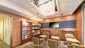 A modern library with bookshelves, seating, and a flat-screen TV. - Ginza Capital Hotel Main (Tokyo)