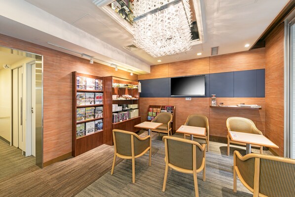 A modern library with bookshelves, seating, and a flat-screen TV. - Ginza Capital Hotel Main (Tokyo)