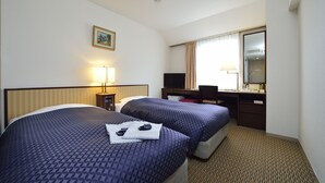 A hotel room with two beds, a desk, a chair, a lamp, and a window with curtains. - Ginza Capital Hotel Main (Tokyo)