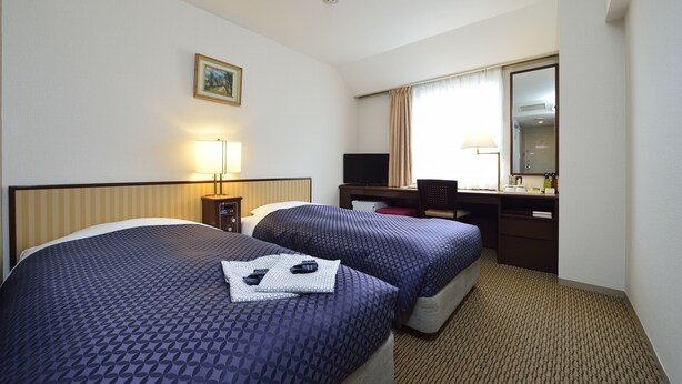 A hotel room with two beds, a desk, a chair, a lamp, and a window with curtains. - Ginza Capital Hotel Main (Tokyo)