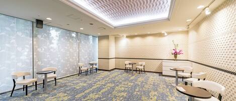 A conference room with a patterned carpet, round tables, and chairs.