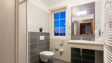 Un baño moderno con inodoro, lavamanos, espejo y ventana.
