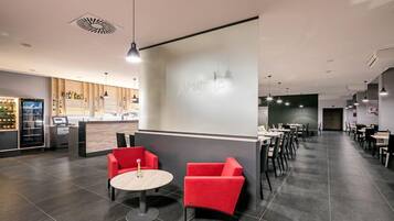 Un restaurante moderno con una zona de bar, asientos rojos y una pantalla grande que muestra el nombre del restaurante.