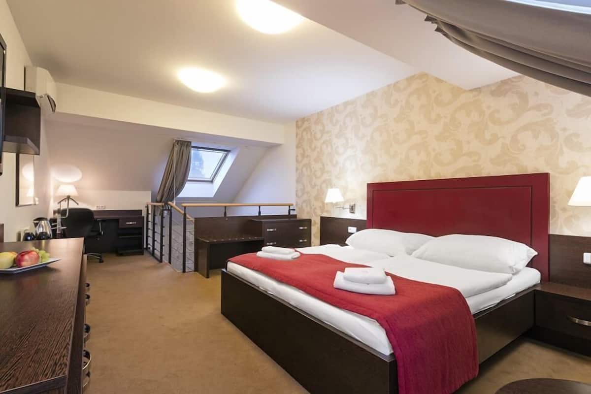 A hotel room with a bed, desk, and chair.