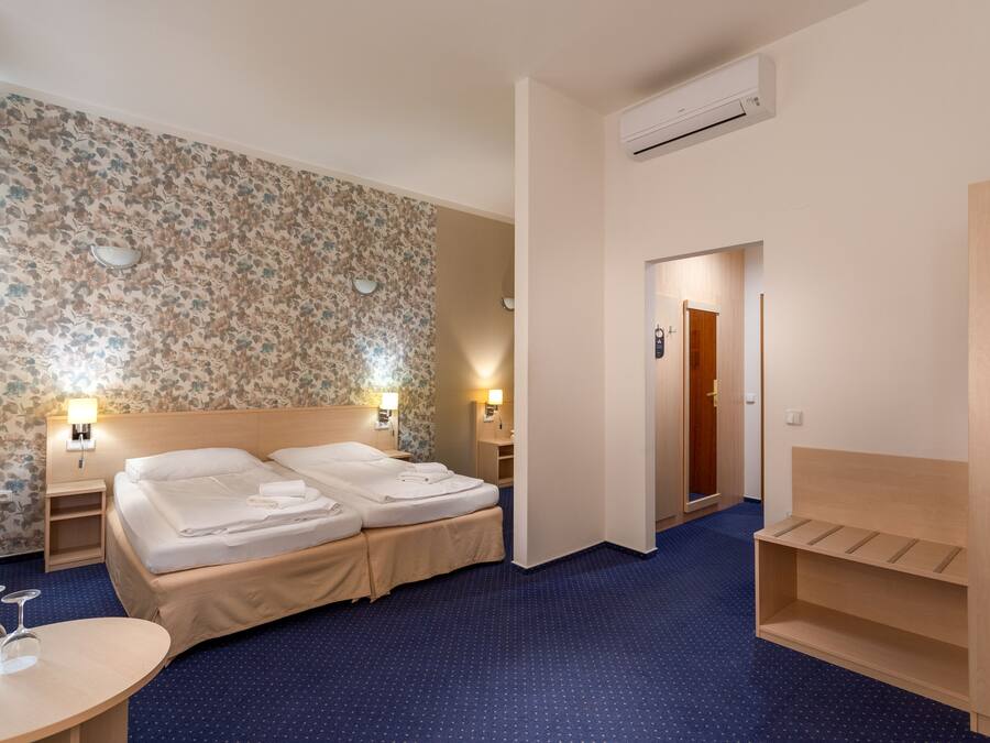 A hotel room with two beds, a desk, and a wardrobe.