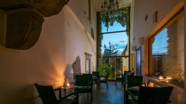 Un interior acogedor con un arco de piedra, una araña y vistas a una escalera que lleva a un balcón.