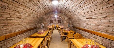 A tunnel-like room with wooden tables and benches, arranged in a semi-circle.