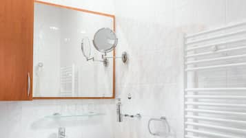 A modern bathroom with a white sink, wooden vanity, a large mirror, and a towel rack.